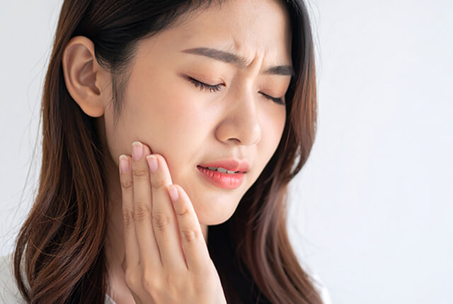 痛そうに頬を押さえている女性